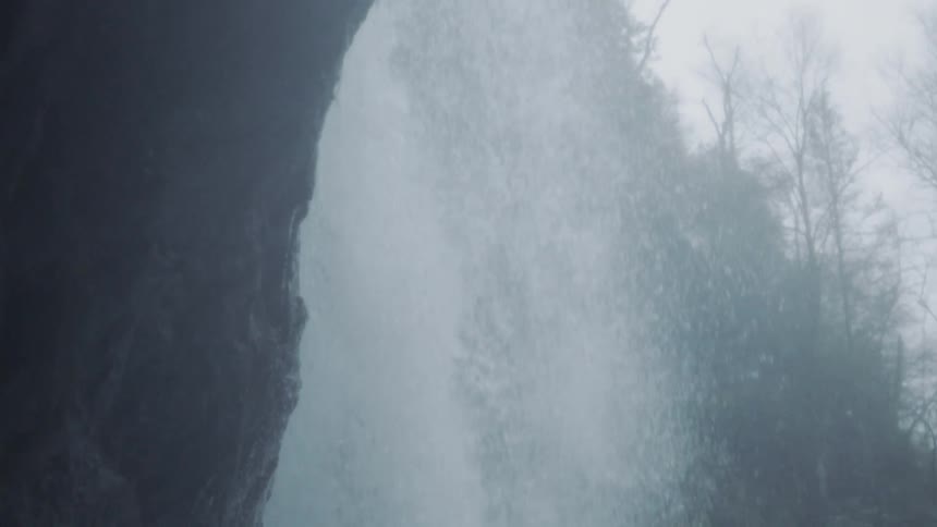 Water cascades down a mountain near some trees
