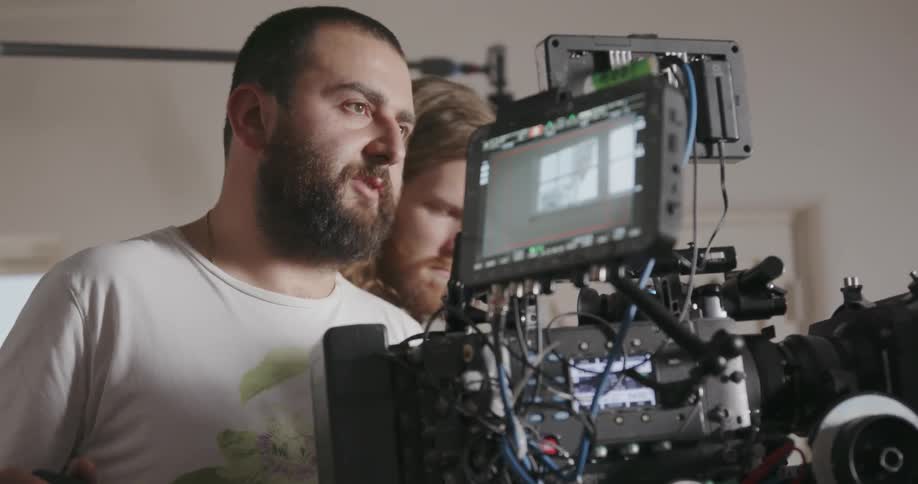 A camera operator talks to people on set