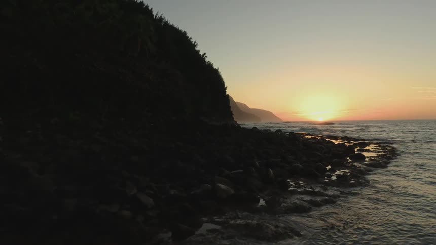 Sun sets over a large body of water and an island