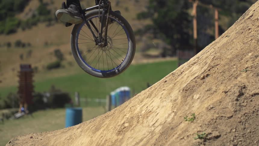 A man jumps over a dirt hill on a bicycle