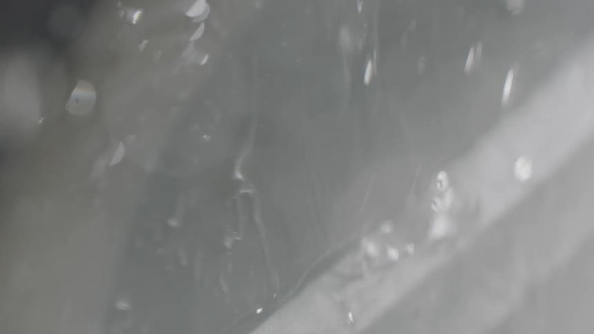 Water is dripping and flooding down a surface in daylight