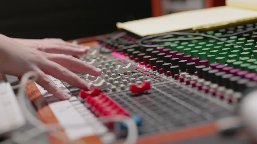 Person tunes knobs on a soundboard