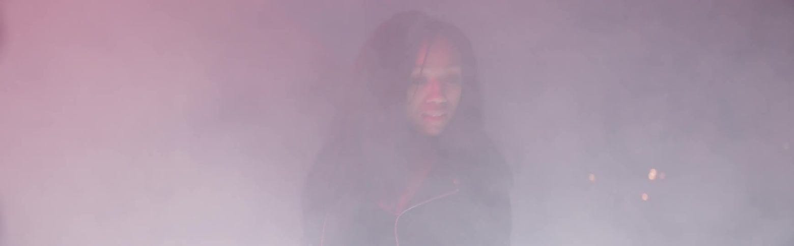 A woman stands and turns in smoke or fog