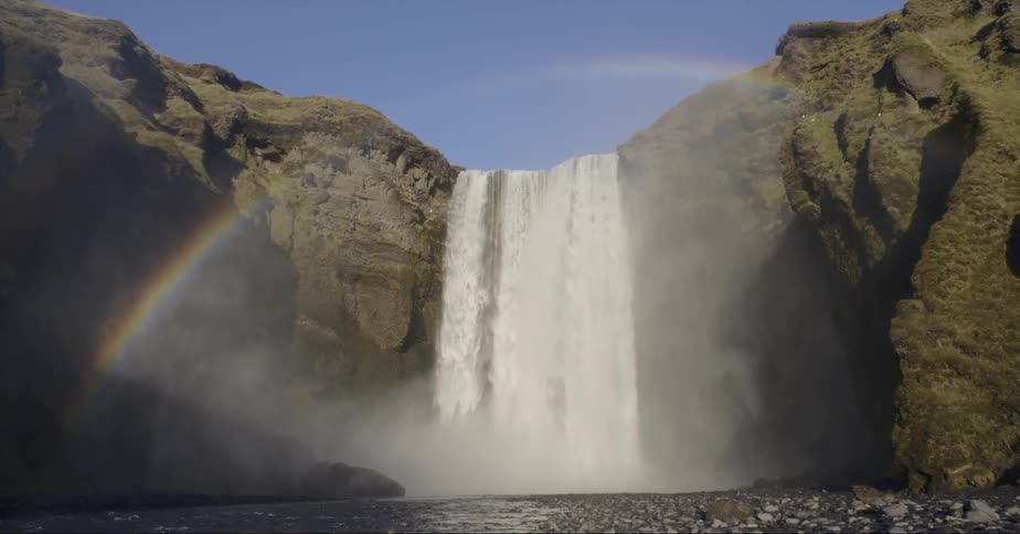 Waterfall splashes into a river creating a rainbow