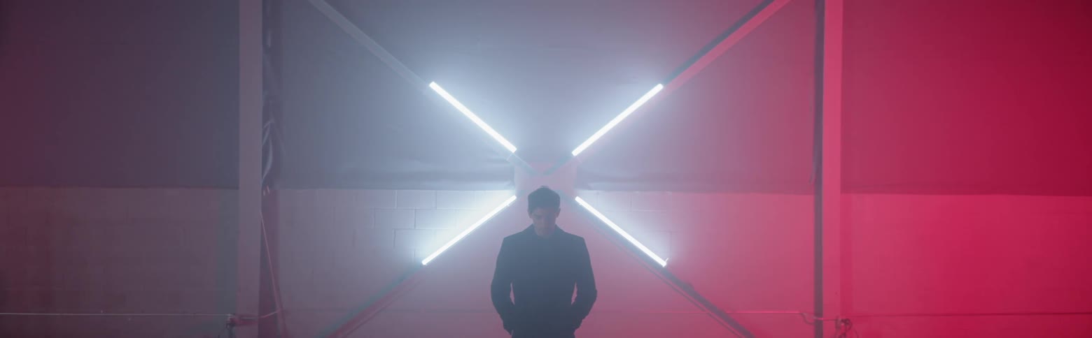 A man stands in front of a wall with fluorescent bulbs
