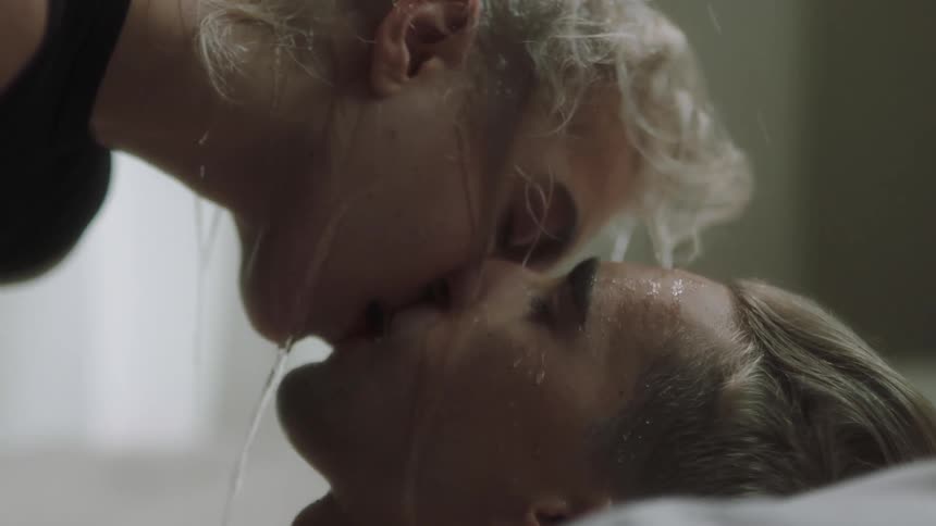 A man and woman kiss while being drenched in water