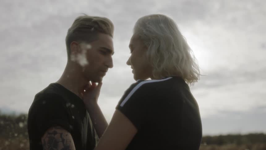 Woman touches man's face outside on a sunny day