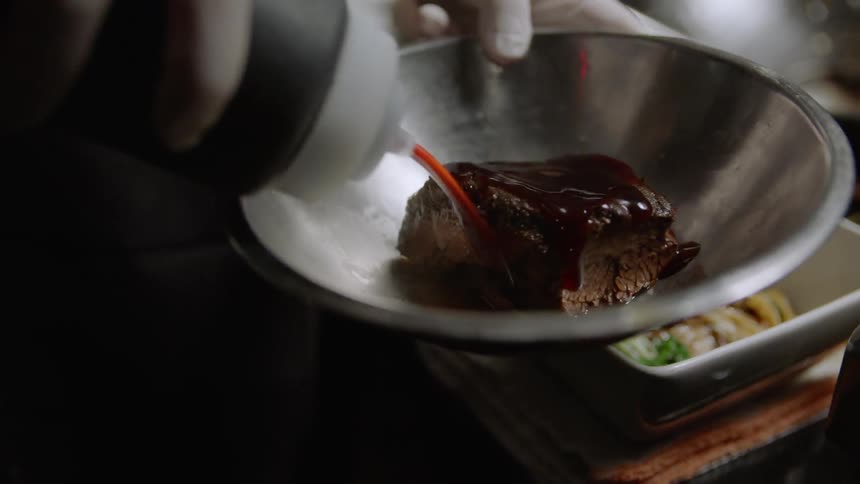 Person puts sauce on food in a bowl