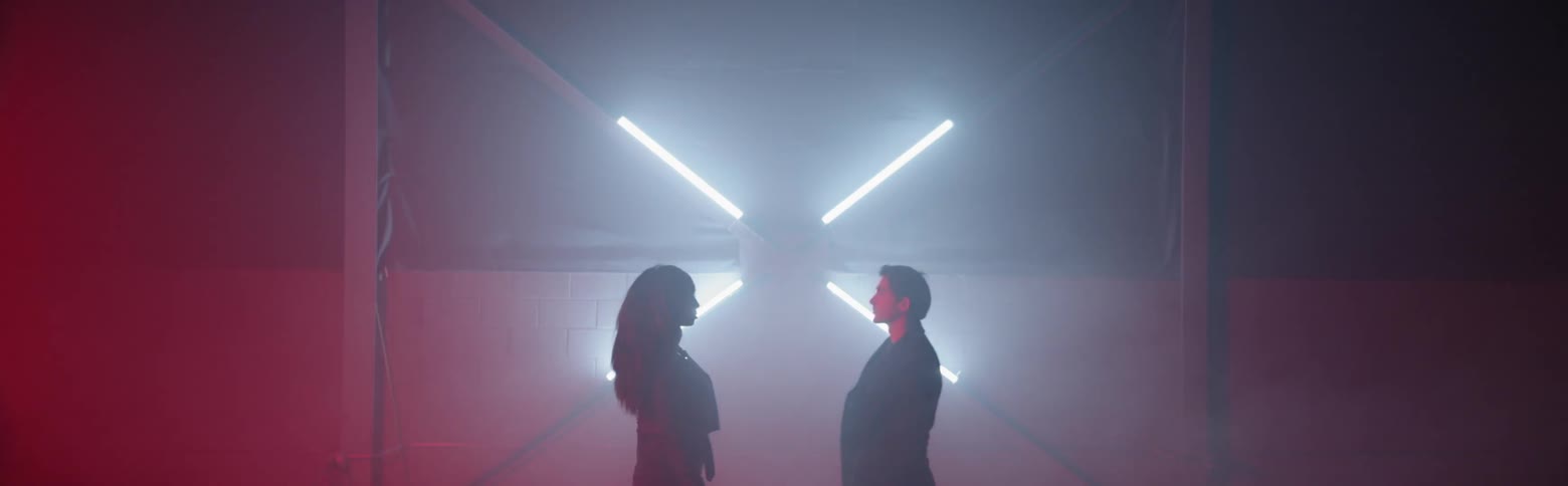 Woman and man walk in a dim room with lights flashing