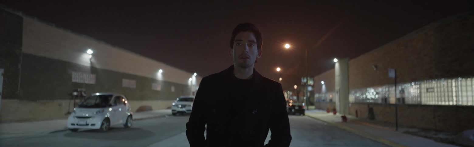 Man looks up as he walks a city street alone at night