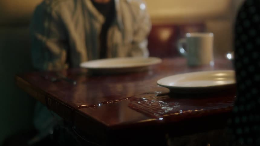 Water is flooding over a diner table as a couple sit in a booth at night