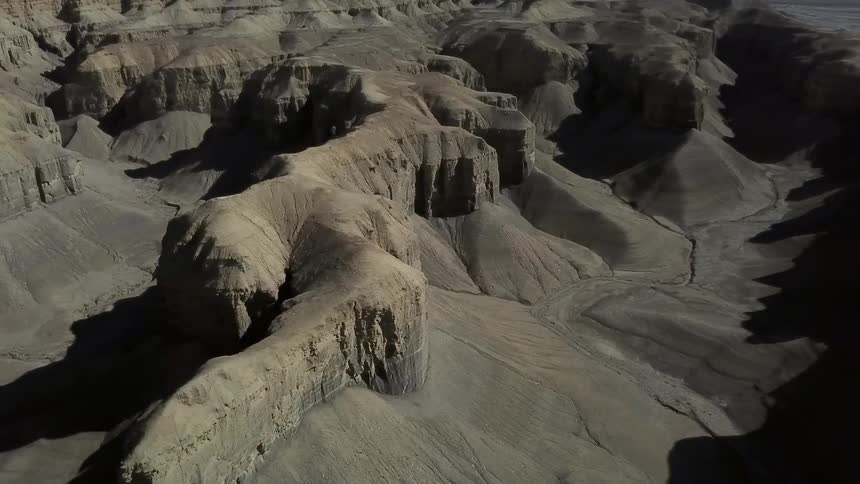 Sand and silt pile up at the base of canyon walls on a sunny day