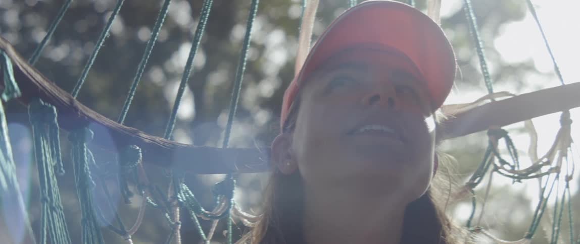 Woman is sitting in hammock outside and smiling