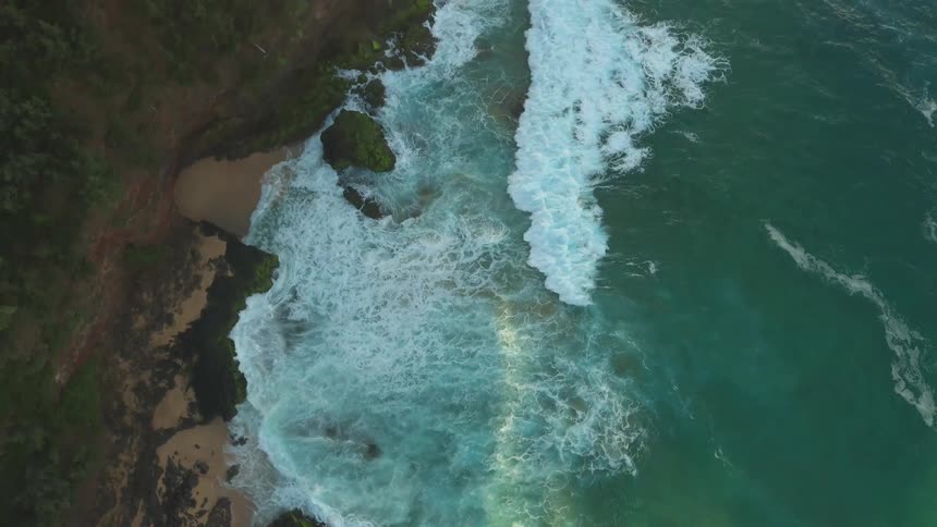 Waves are rolling and crashing towards a beach during the day