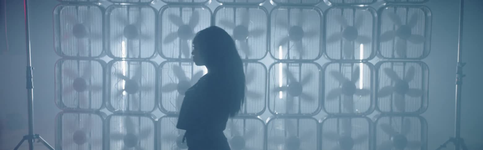A woman walks past a wall of box fans