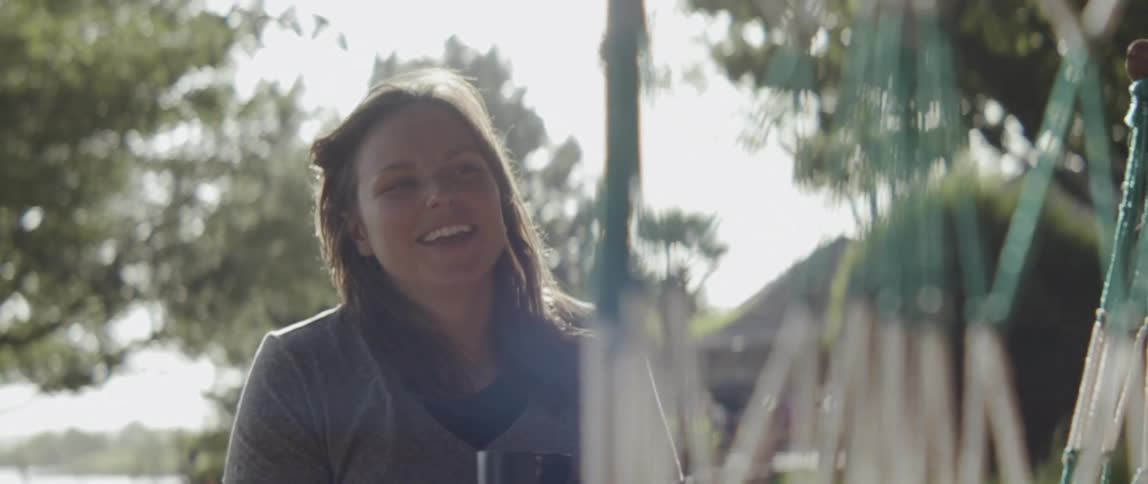A woman smiles and drinks outside