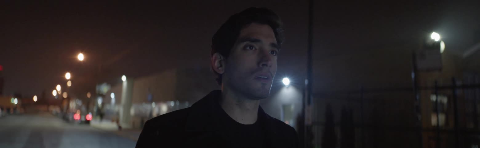 Man stands outside on a city street at night