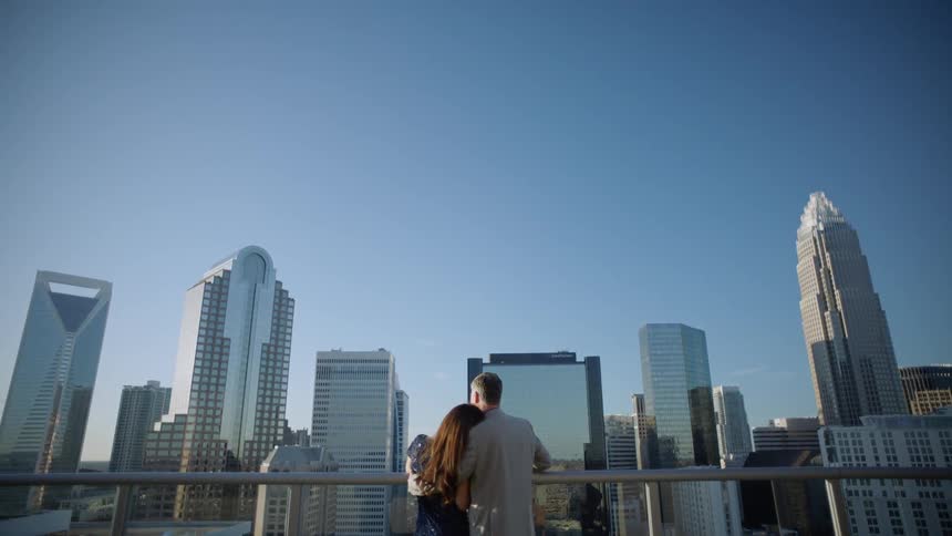 A couple embrace on a roof deck overlooking the city