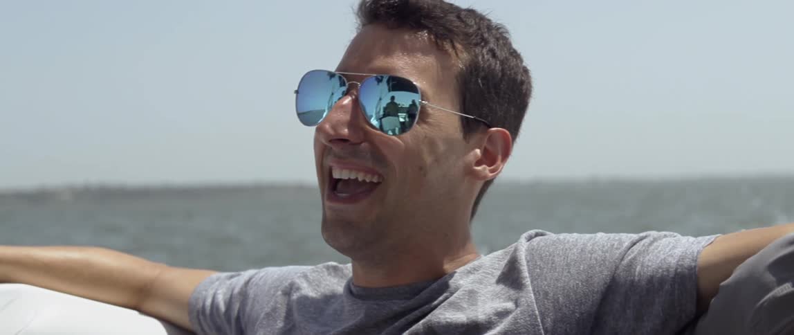 Smiling man rides on a boat on a sunny day