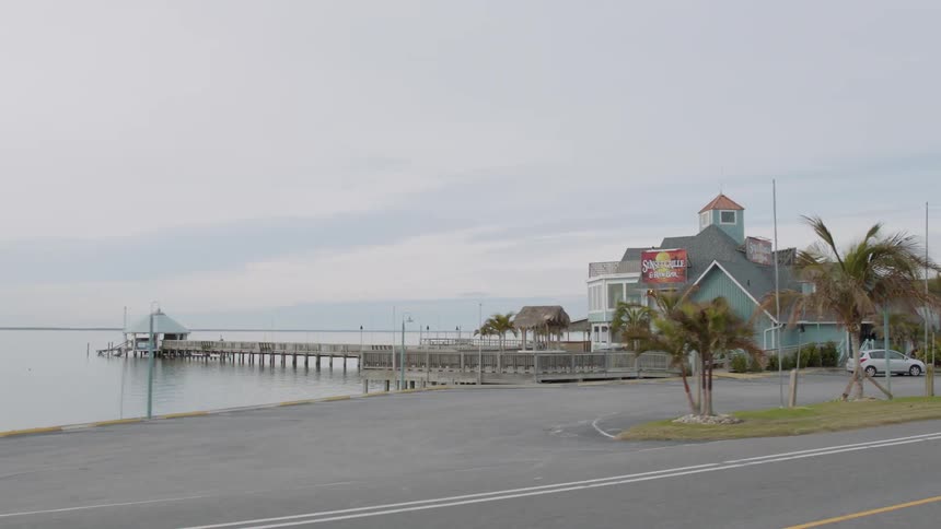 Long pier extends into the water near a blue building