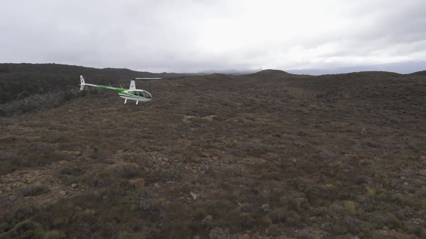 Helicopter flying over a large field on a cloudy day