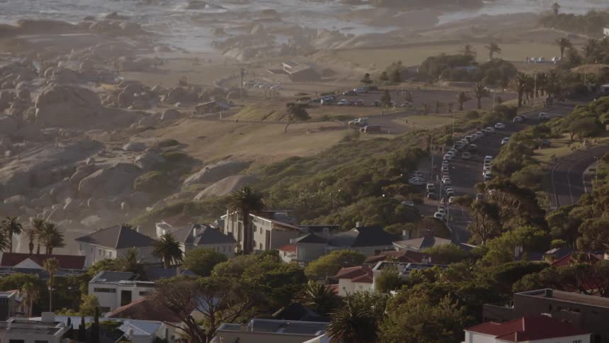 Haze is lingering in the air over a community on a rugged coastline during the day