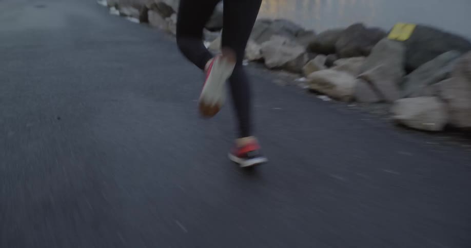 Woman runs down a street next to some rocks