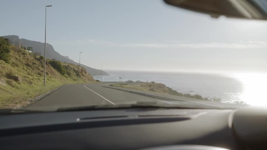 Car drives on a country road next to a large body of water