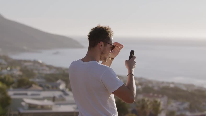 Man stands on a hilltop looking at his phone