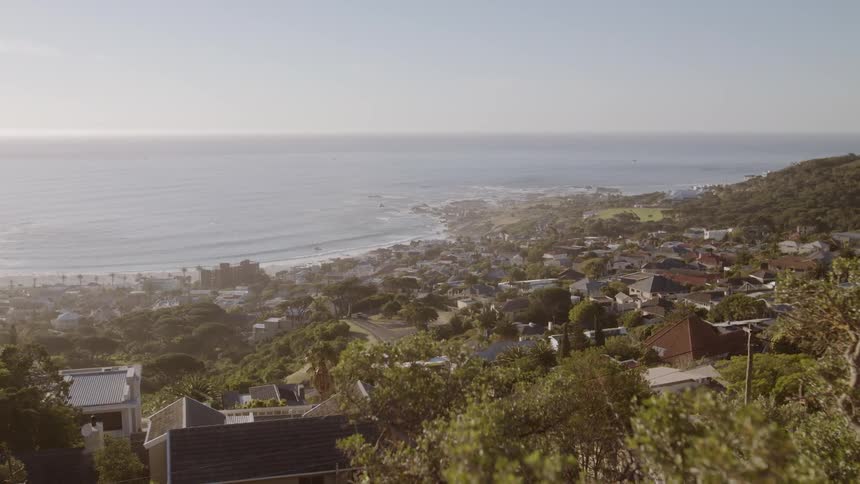 Houses and trees cover the hill by the beach shore