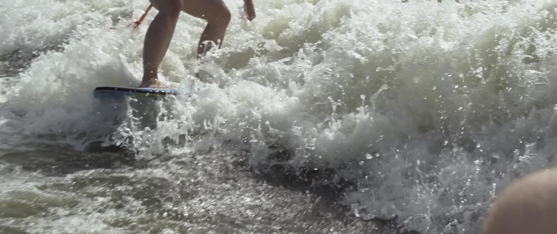 A surfer rides a wave on a sunny day