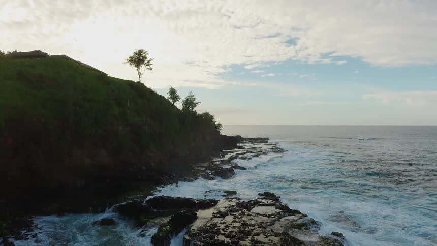 The ocean tide flows towards the rocky shore