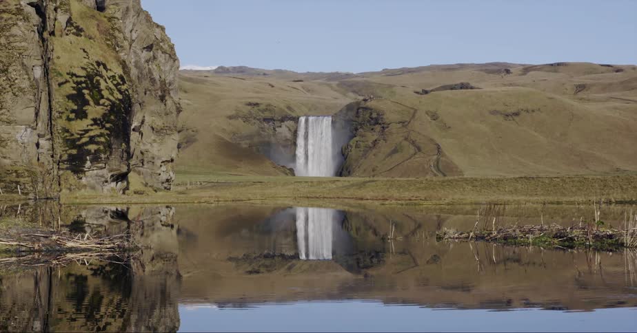 Large waterfall flowing off mountain on sunny day