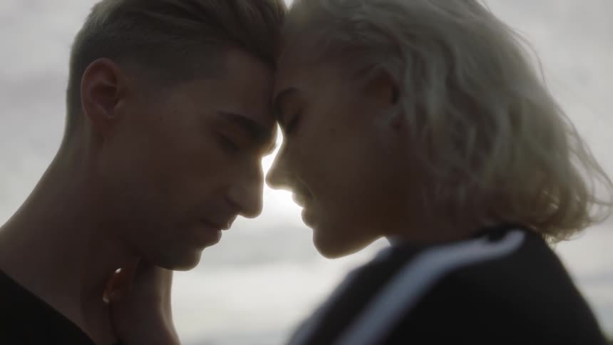 A man and woman stand face to face outside