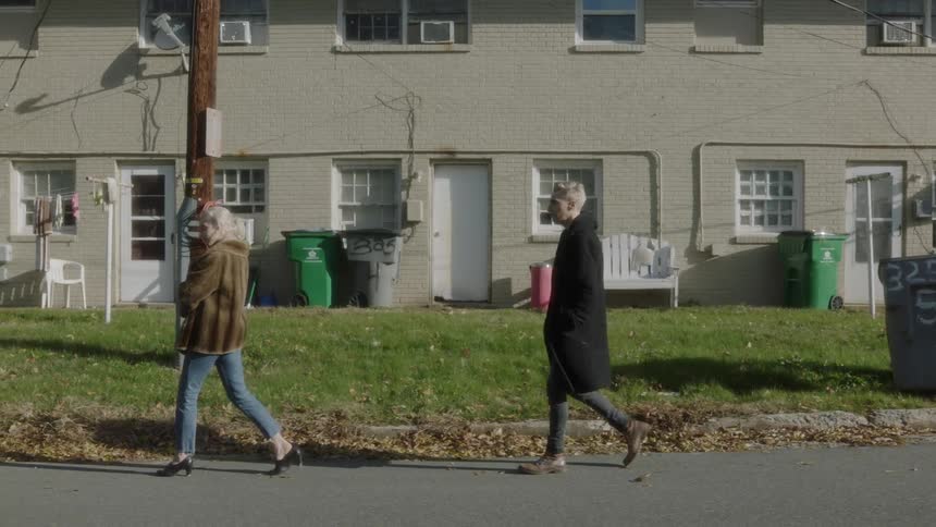 Man walking behind woman on neighborhood street on sunny day