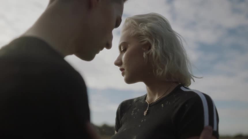 A man and woman face each other while snowflakes fall on them