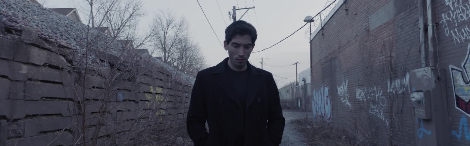 A man walks down a graffiti filled alley