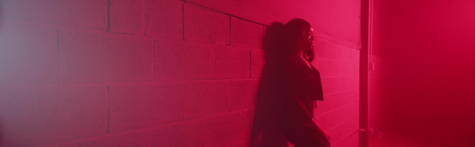 A woman leans against a concrete wall