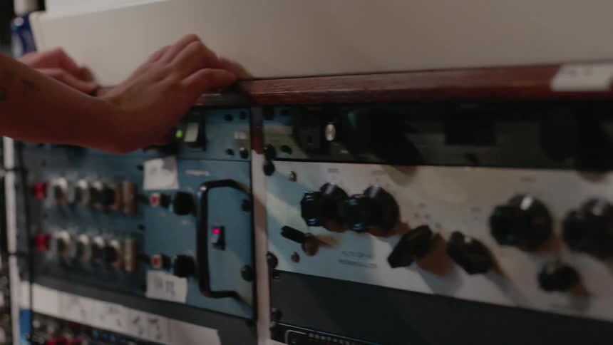 A person adjusts a synthesizer rack