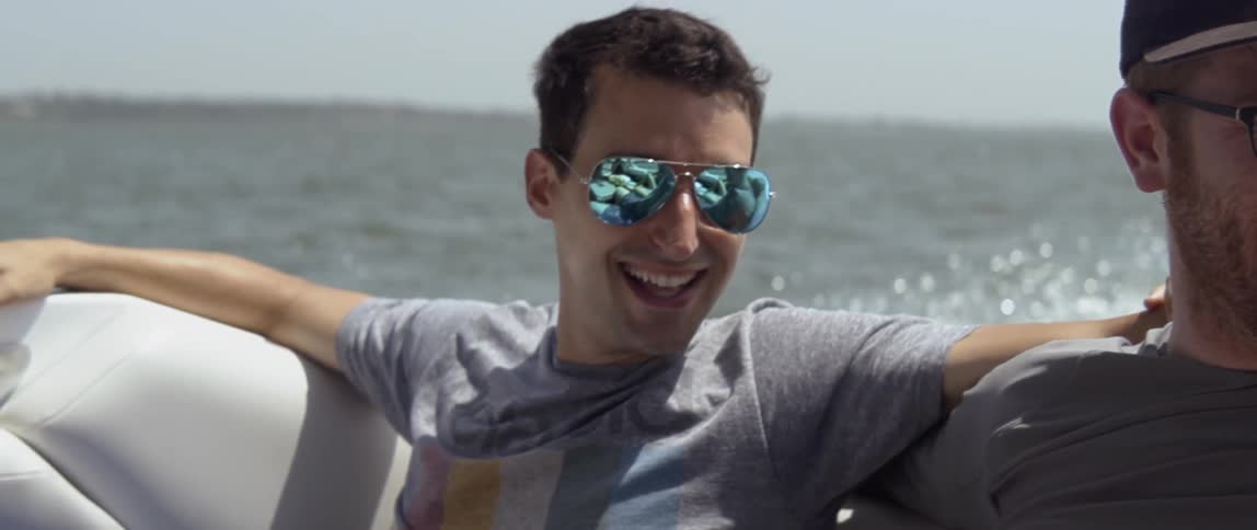Man smiles while riding on a boat on the water