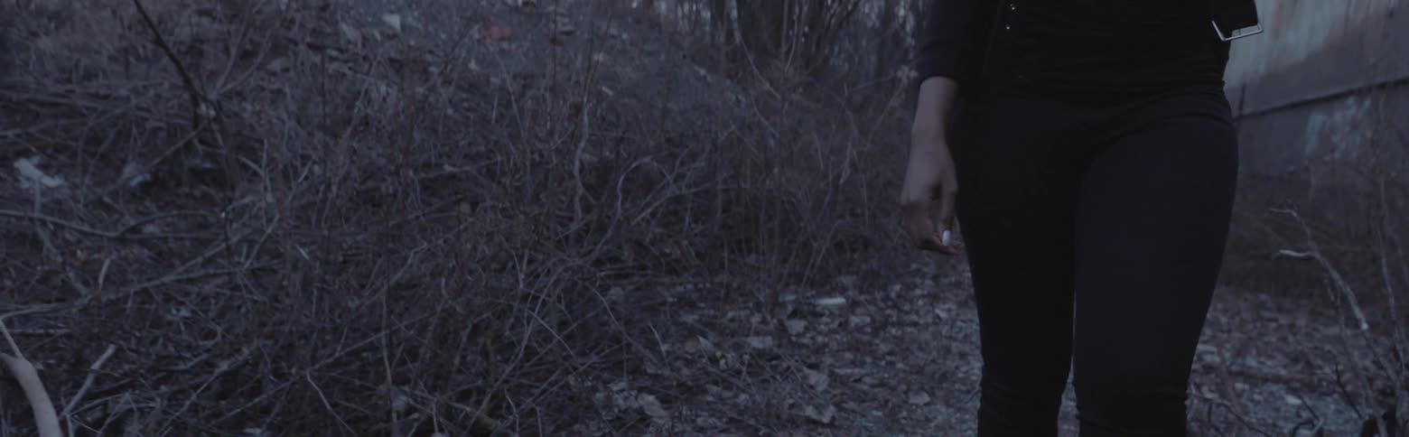 A woman in ankle boots walks through the brush