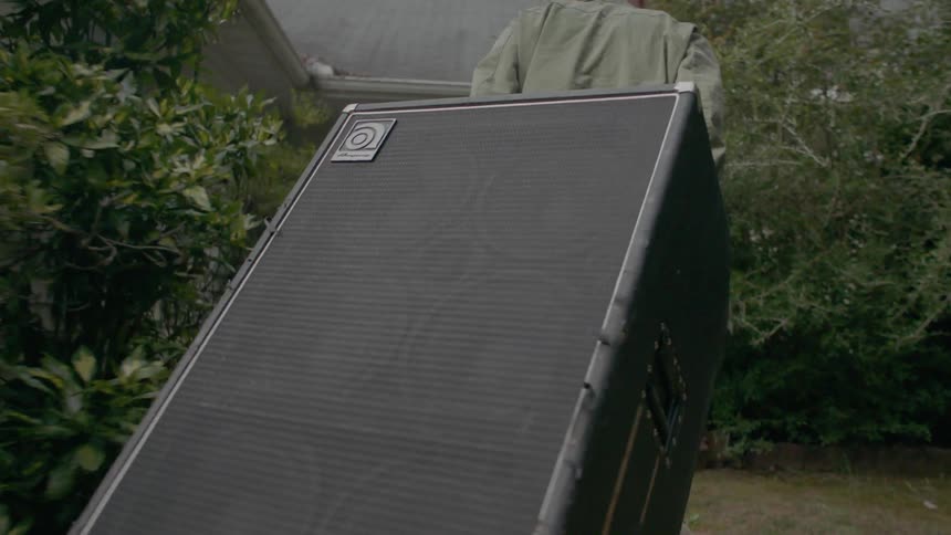 A man is towing an equipment case into a house in daylight