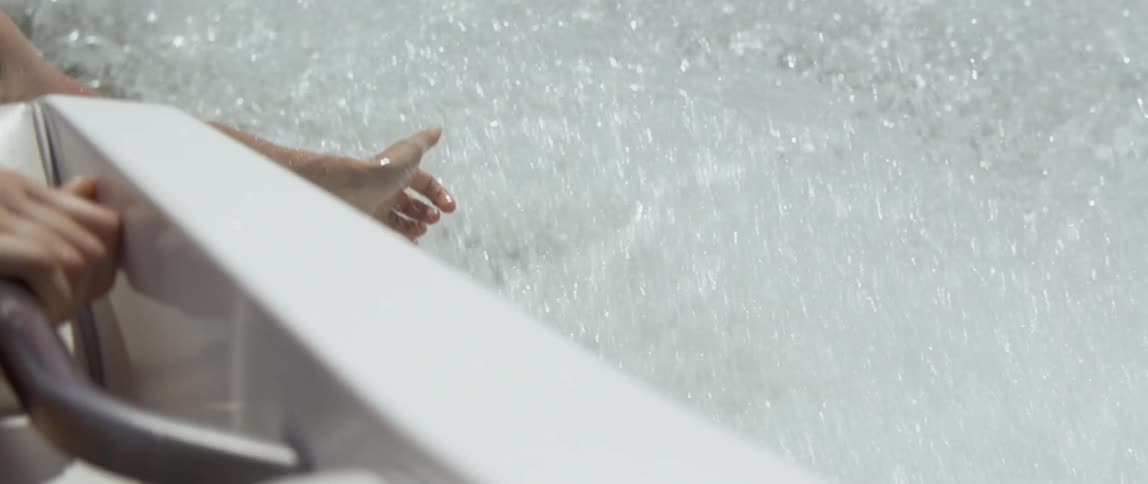 A person sticks their hand in the water from a boat