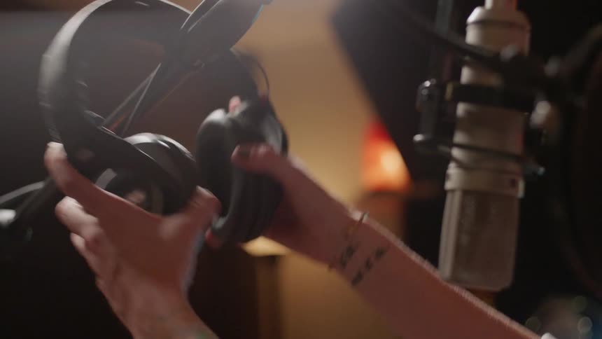 A woman grabs headphones off of a mic stand