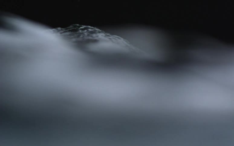Fog rolls over flowing water in the dark