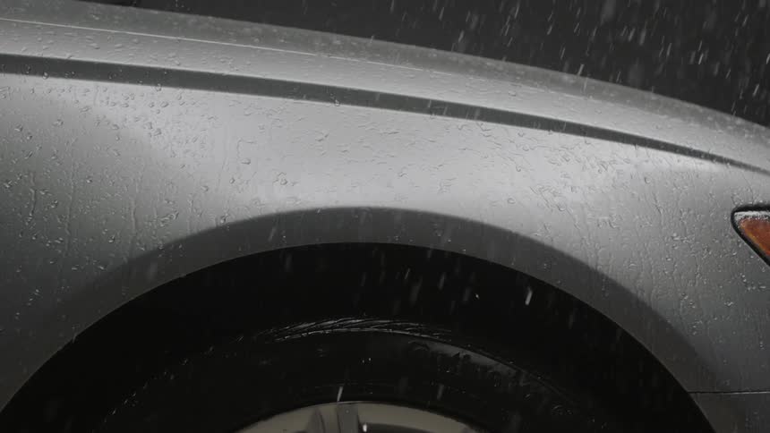Rain falls into a silver vehicle at night