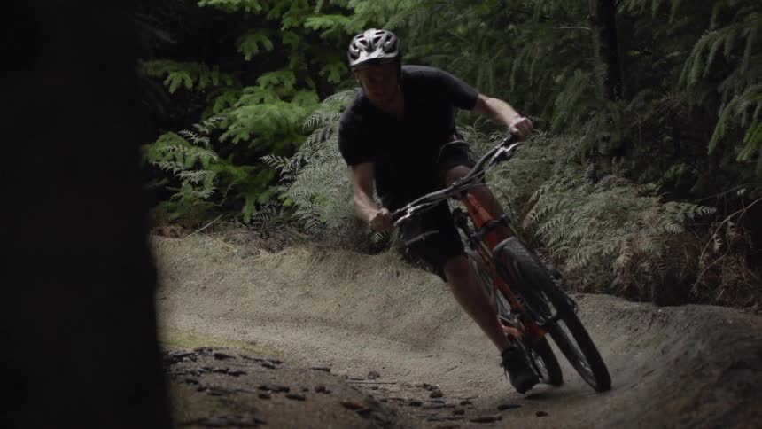A boy rides a dirt bike on a narrow path in the forest