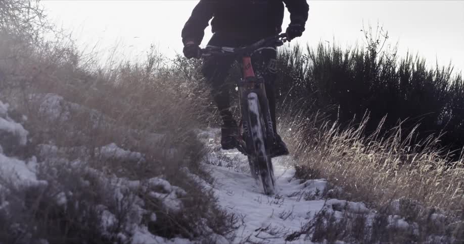 A man is riding his bike along a snow covered trail