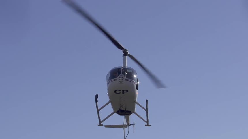The blades on a helicopter rotate as it hovers in the sky