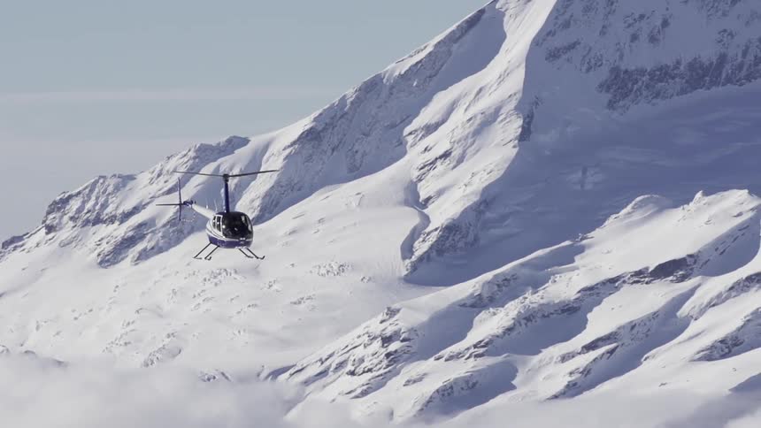 A helicopter flying by snowy mountains